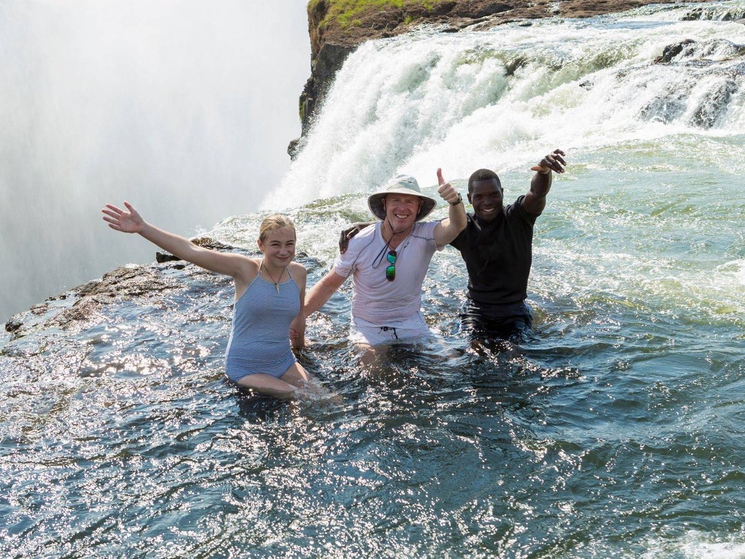 Tourists enjoying the scenic view of Victoria Falls at Devil’s Pool experiences one of Southern Africa’s most thrilling natural attractions on a trip organized by Pieland Gorilla Safaris. Standing close to the dramatic edge of the falls, the traveler watches the powerful Zambezi River plunge into the deep gorge below while mist rises across the surrounding cliffs. The natural rock pool provides a remarkable perspective of the waterfall and creates unforgettable photography opportunities. With experienced guidance and careful attention to safety, the visit becomes an exciting combination of adventure, scenery, and discovery in one of Africa’s most spectacular destinations.