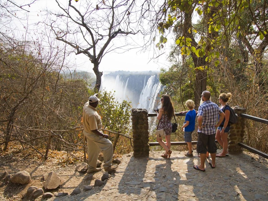 A family enjoys the spectacular views of the mighty Victoria Falls as their experienced guide shares fascinating stories about the history, formation, and significance of this natural wonder during their 7 Days Victoria Falls Family Safari. Standing at the viewpoints, they admire the powerful cascades, rising mist, and breathtaking scenery while capturing unforgettable moments together. The guided experience allows the family to learn more about one of Africa’s greatest attractions while creating lasting memories surrounded by the beauty and adventure of Victoria Falls.