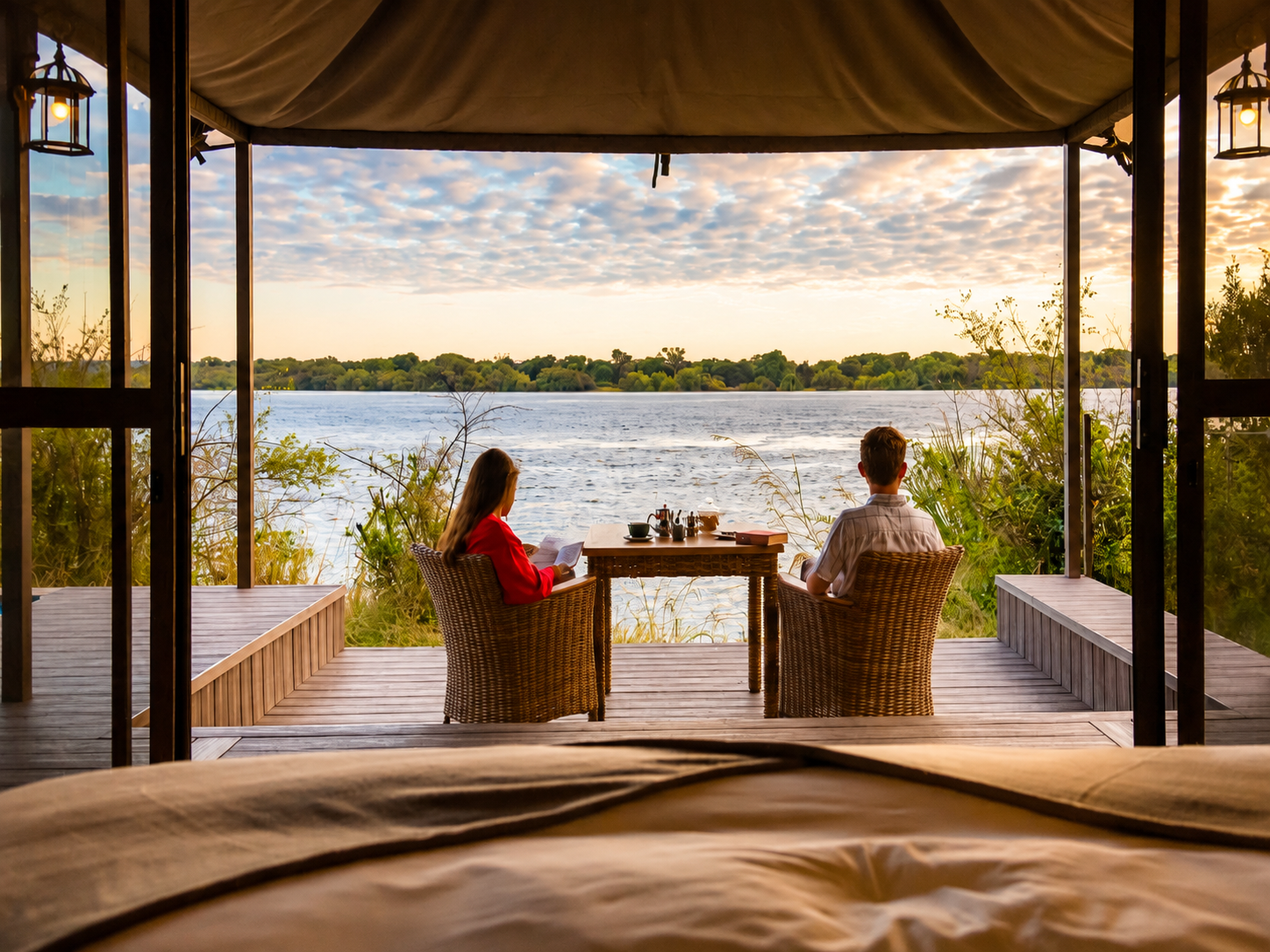 Couple relaxing on a private riverside lodge deck with scenic river views during a romantic Victoria Falls honeymoon safari.