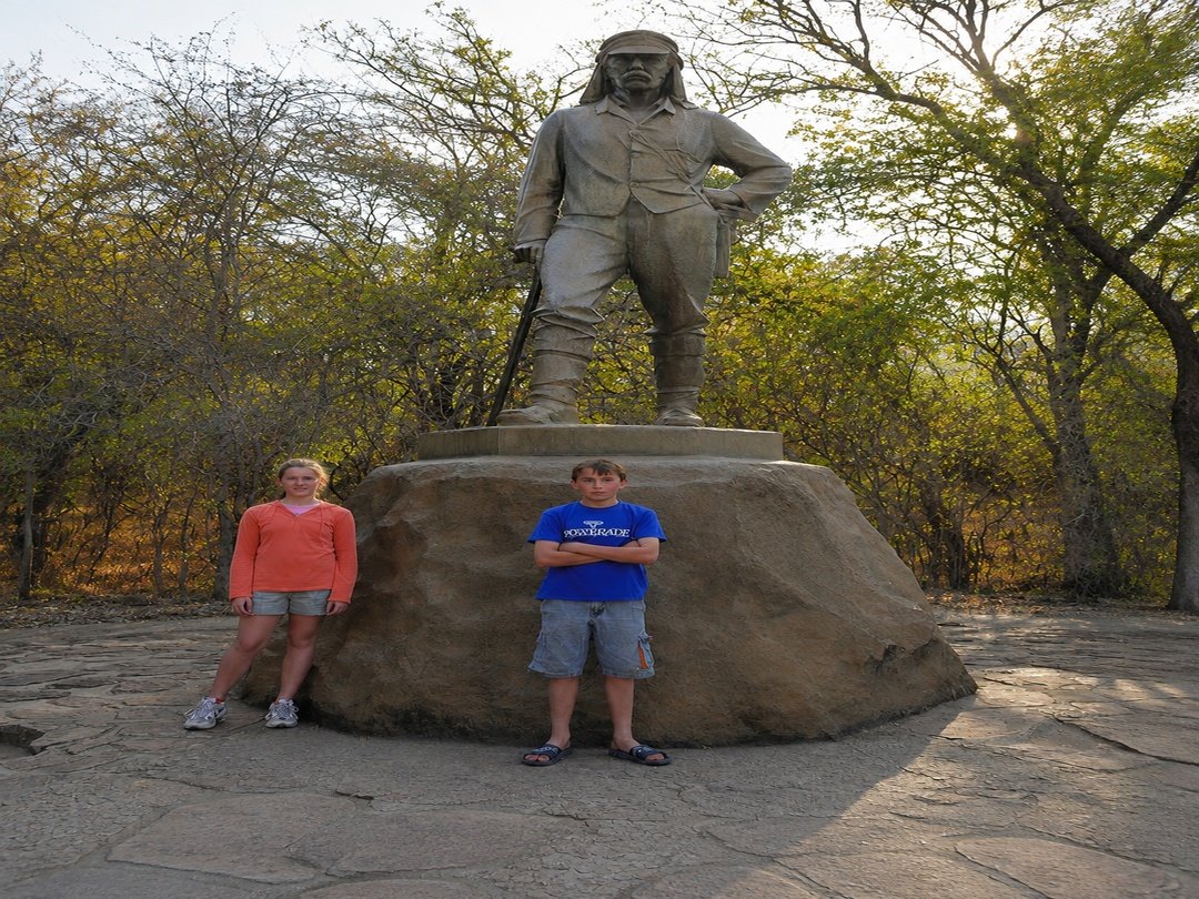 Tourists stand beside the bronze statue of Scottish explorer Dr. David Livingstone at Victoria Falls, capturing a memorable moment at this historic landmark. The statue honours Livingstone’s exploration of the Zambezi River and his famous discovery of the magnificent falls. Visitors enjoy learning about the area’s history while experiencing the beauty and cultural significance of one of Africa’s greatest natural wonders.