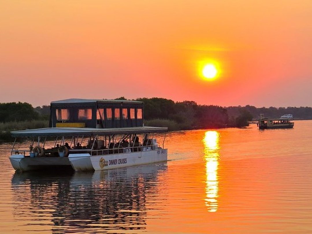 Tourists enjoy a relaxing Zambezi River sunset cruise during their Victoria Falls and Chobe Safari, gliding gently across the calm upper Zambezi as the sun begins to set. Golden and orange colors reflect across the water, creating a peaceful atmosphere after a day of sightseeing and wildlife experiences. Along the riverbanks, guests may spot hippos, crocodiles, elephants, and a variety of birdlife while enjoying the cool evening breeze. The cruise offers beautiful photography opportunities and a memorable contrast to the excitement of Victoria Falls and Chobe National Park, making it a perfect way to end the day.