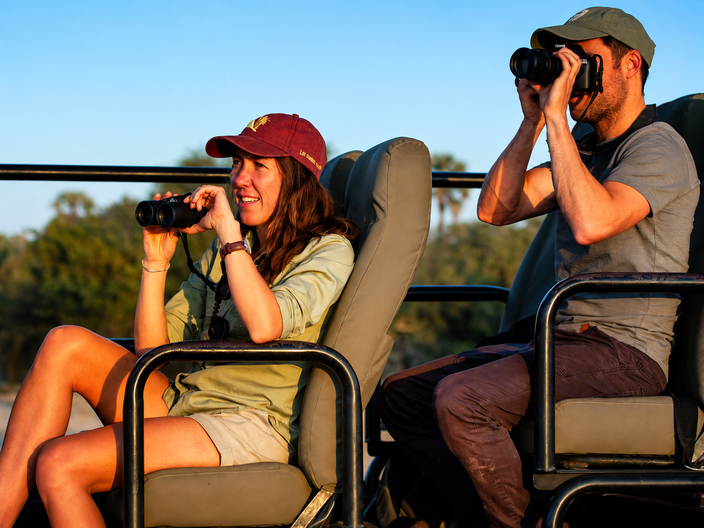 Couple enjoying a game drive safari experience in an open vehicle while exploring African wildlife and scenic savannah landscapes.