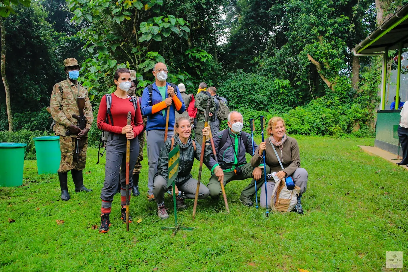 Older travelers gather at the park headquarters early in the morning, dressed in hiking clothes and holding walking sticks, cameras and small daypacks. Rangers welcome the group and explain what to expect in the forest, including safety rules, walking conditions, wildlife behavior and the importance of following instructions. Some travelers sit on benches while others stretch gently or speak with porters who will assist them along the trail. There is a mixture of excitement, curiosity and quiet anticipation as everyone prepares mentally for the journey ahead. Soon, groups are organized according to ability, and the travelers begin their unforgettable forest adventure.