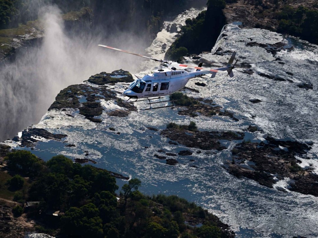 Tourists enjoying a 15-minute Victoria Falls helicopter tour with breathtaking aerial views of the waterfall, Zambezi River, Batoka Gorge, and surrounding landscapes.