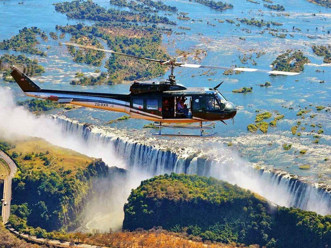 Tourists enjoying a 22-minute Victoria Falls helicopter tour with spectacular aerial views of the waterfall, Zambezi River, Batoka Gorge, and surrounding landscapes.