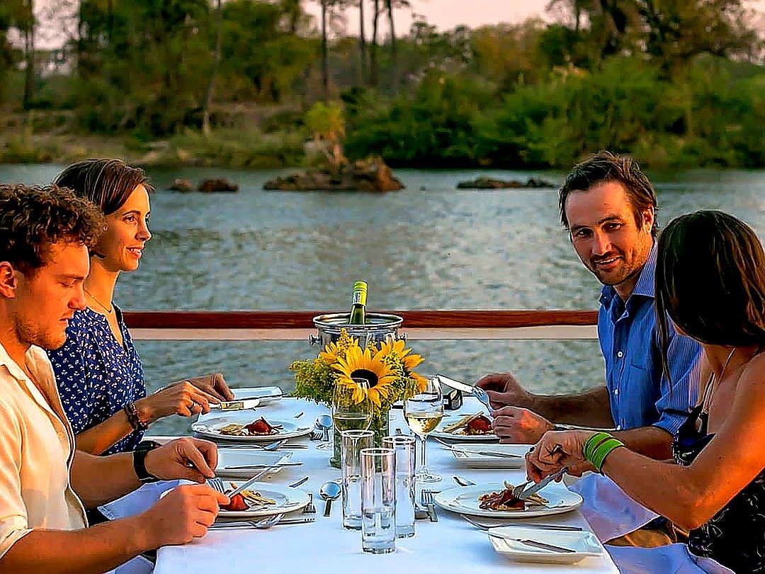 A Family enjoying a romantic Zambezi River boat cruise near Victoria Falls with beautiful river views and a peaceful sunset atmosphere