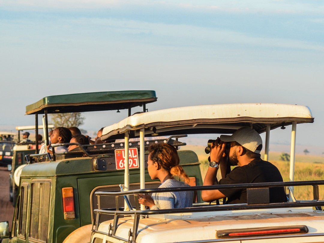 Tourists enjoying a game drive through Uganda’s savannah plains in a 4x4 safari vehicle while searching for wildlife