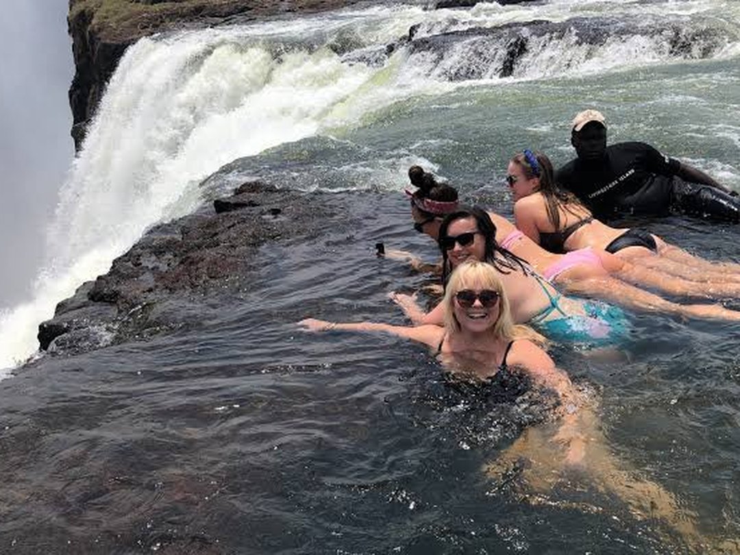 Tourists enjoying a swimming experience at Livingstone Island with views of the Zambezi River