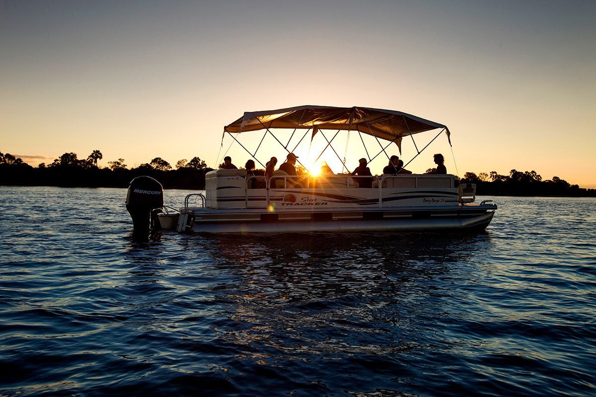 Tourists enjoying the sunset on the Zambezi River during a relaxing river cruise near Victoria Falls