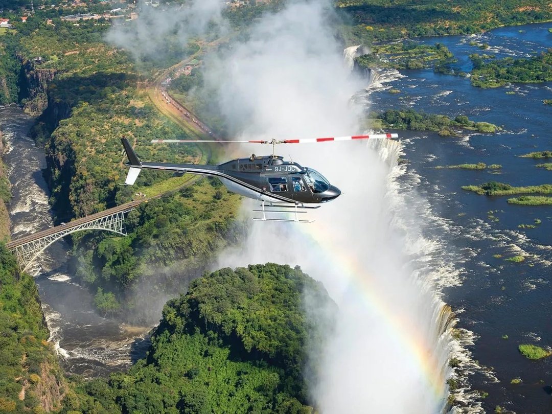 A family enjoying a Victoria Falls helicopter tour, admiring spectacular aerial views of the waterfall, Zambezi River, and surrounding landscapes.