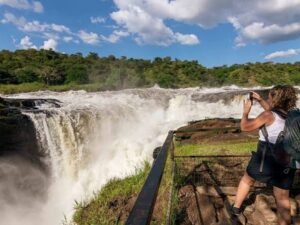 Traveller photographing the powerful Murchison Falls from the Top of the Falls viewpoint in Uganda.