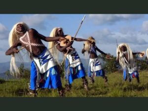 Traditional Rwandan Intore dancers performing with spears, long white headdresses and colourful costumes.