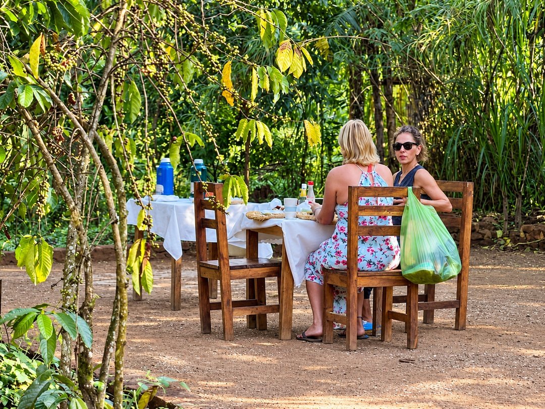 Tourists relaxing at Little Monkey Camp near Kibale National Park, surrounded by a peaceful tropical garden setting.