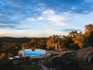 Scenic safari lodge swimming pool overlooking a forested African landscape at sunset